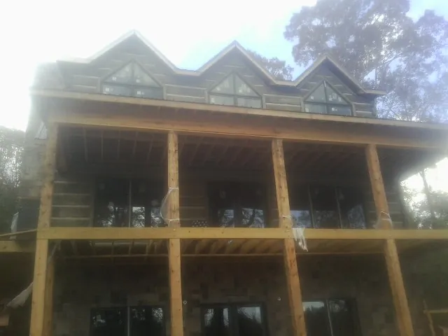 Dormers and porch framing on a large log home under construction — Roof Coating work by our crew in Roswell