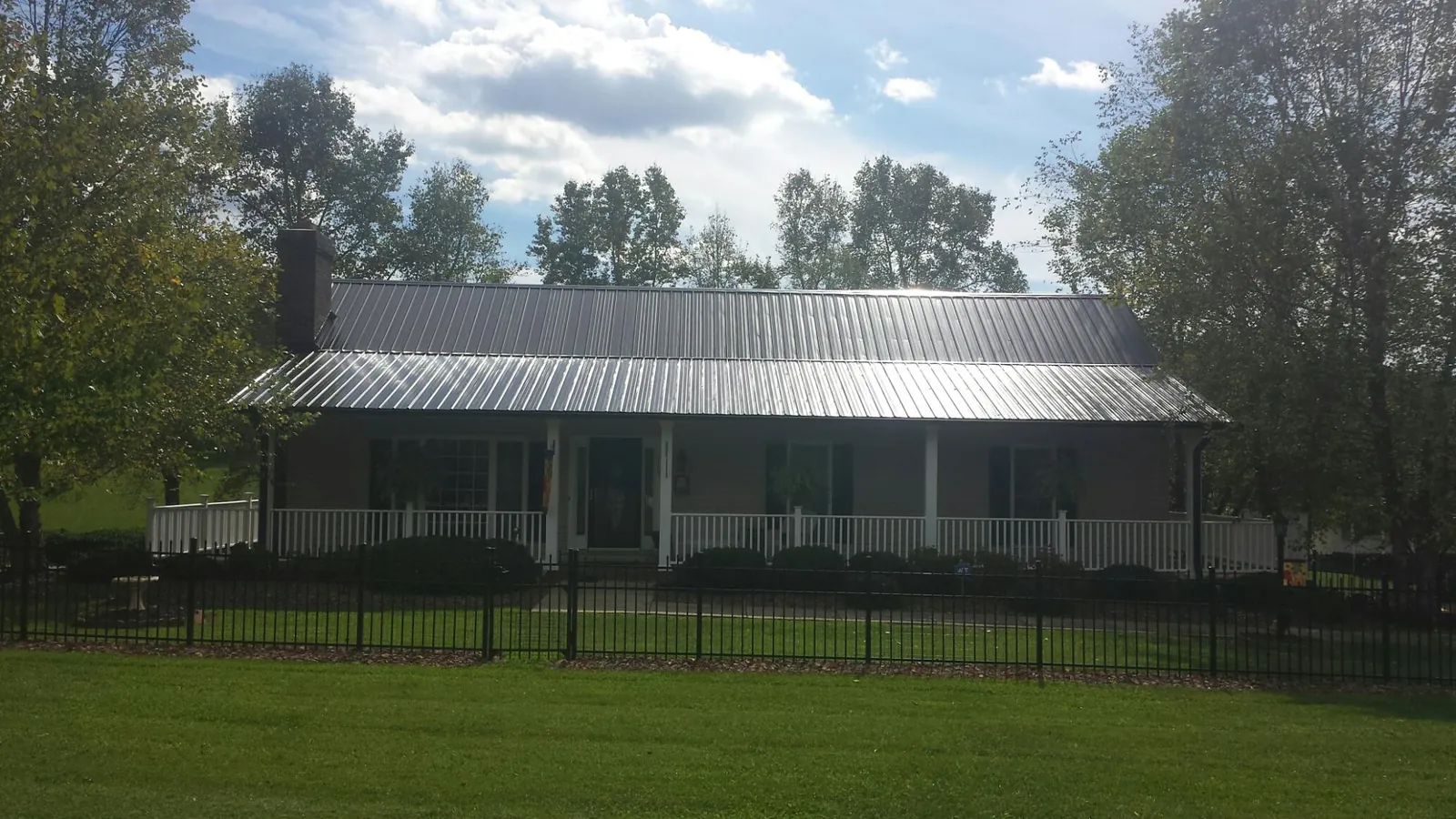 Gray metal roof on a brick ranch with a full width front porch — Gutter Guard Installation work by our crew in Roswell
